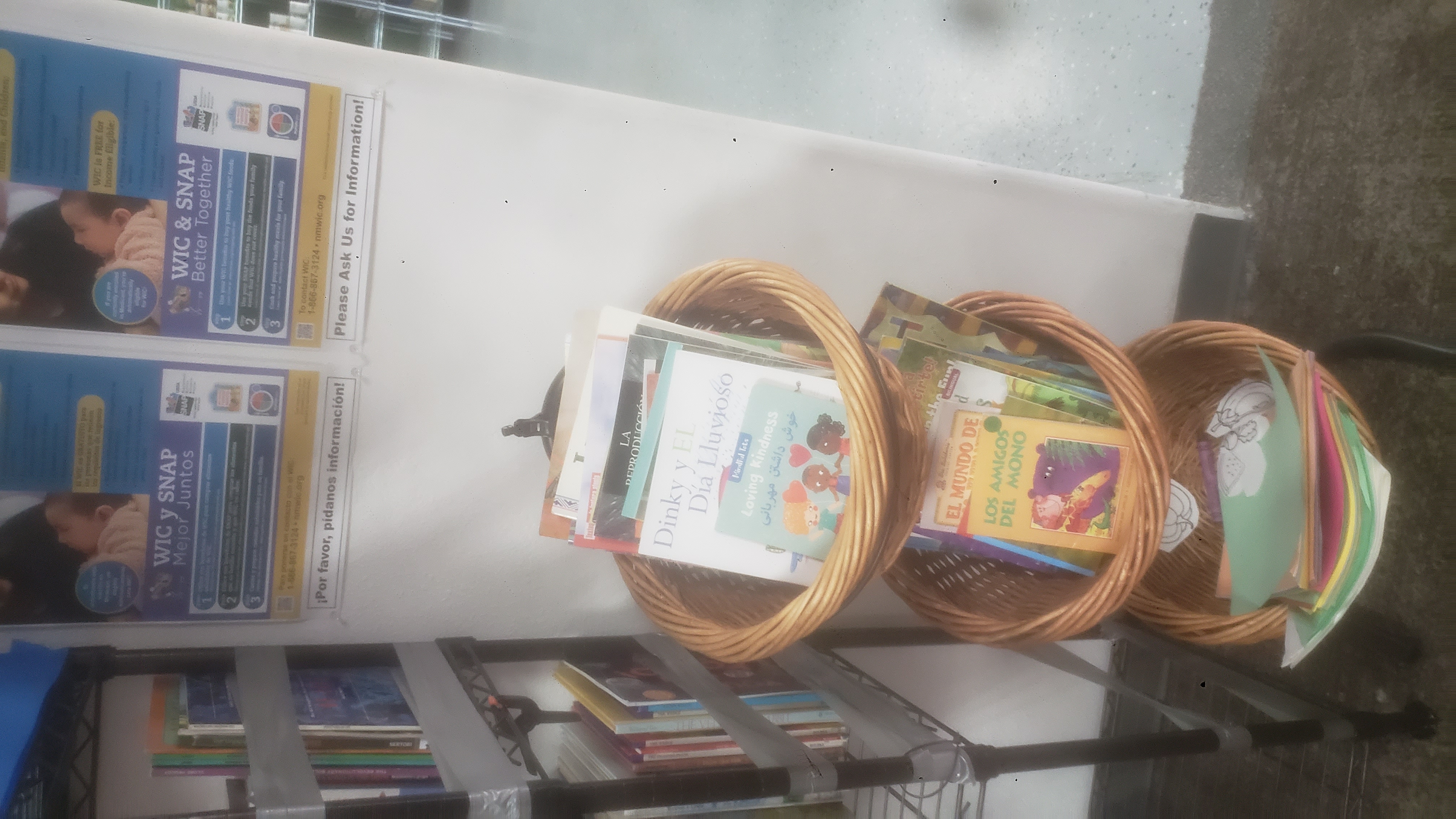 3 tier display baskets filled with books next to shelf of books.
